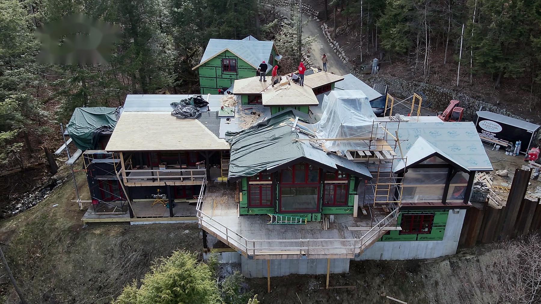 Aerial view of a Lake Champlain Roofing crew re-roofing a large lakeside home