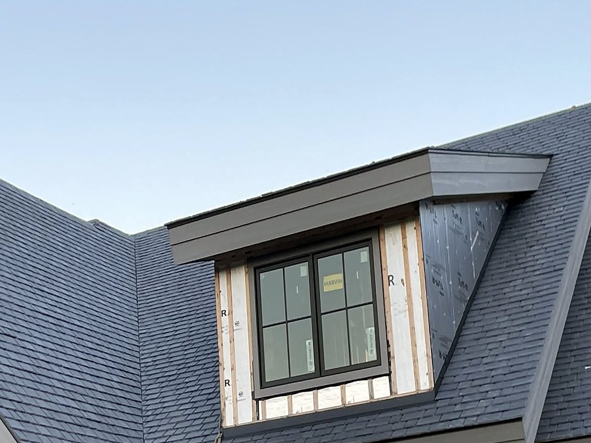 New-construction dormer wrapped in custom dark sheet metal trim and fascia