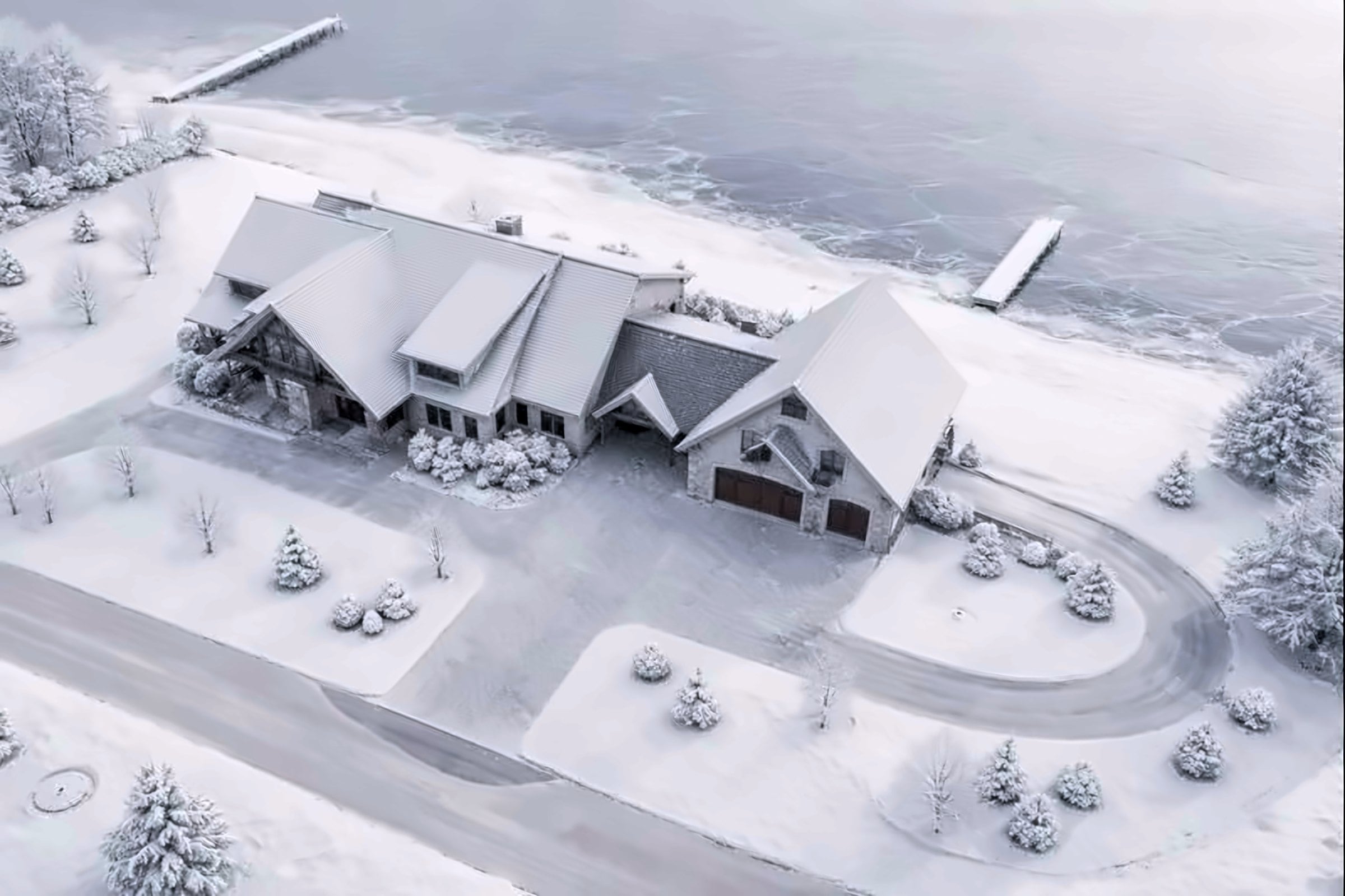 Aerial view of a lakeside home with a new roof under fresh snow
