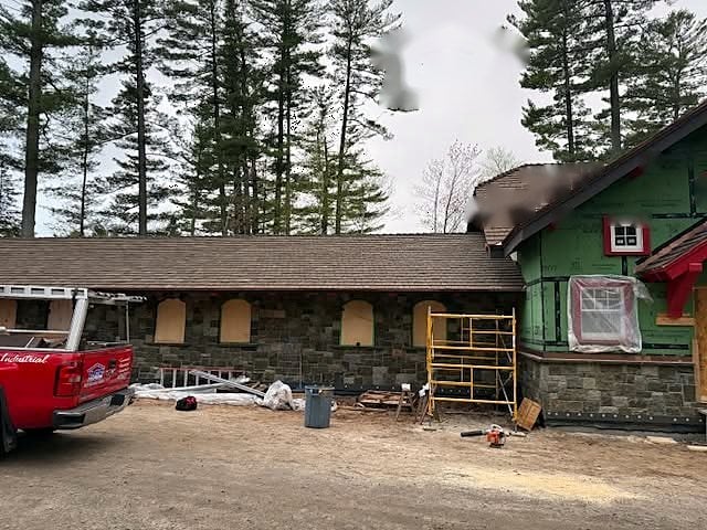 Stone house with a new roof and a Lake Champlain Roofing truck in the driveway